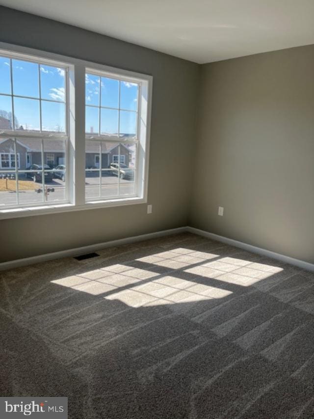 carpeted empty room featuring visible vents and baseboards