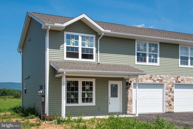 view of front of house with a garage, stone siding, a shingled roof, and aphalt driveway