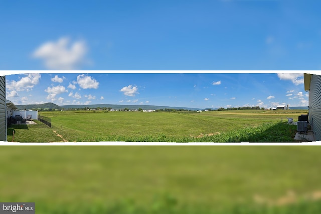 view of home's community with a mountain view, a yard, and a rural view