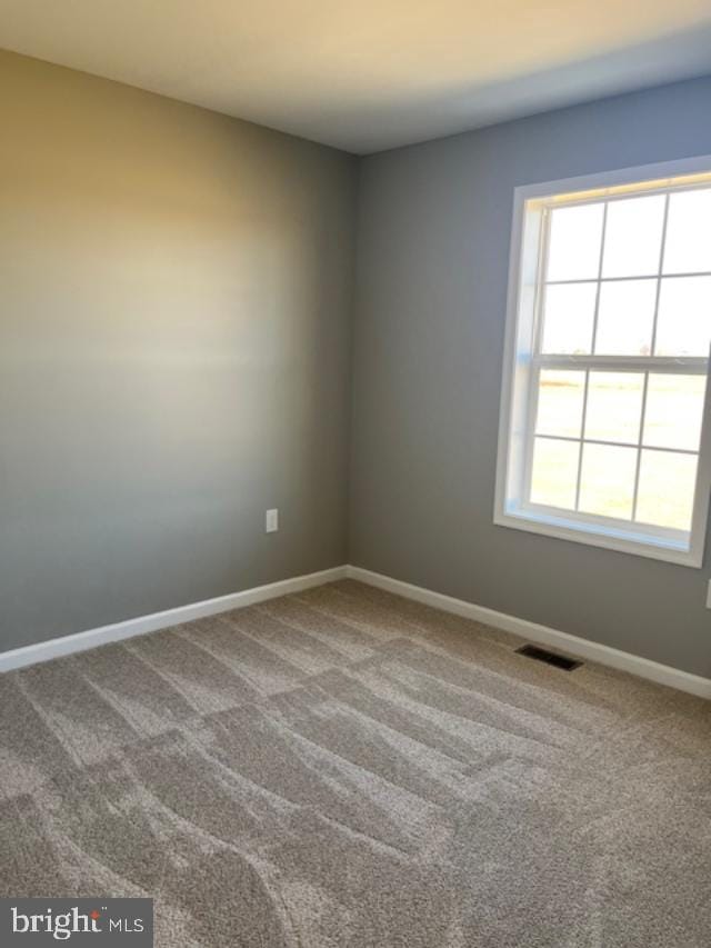 carpeted empty room with visible vents and baseboards