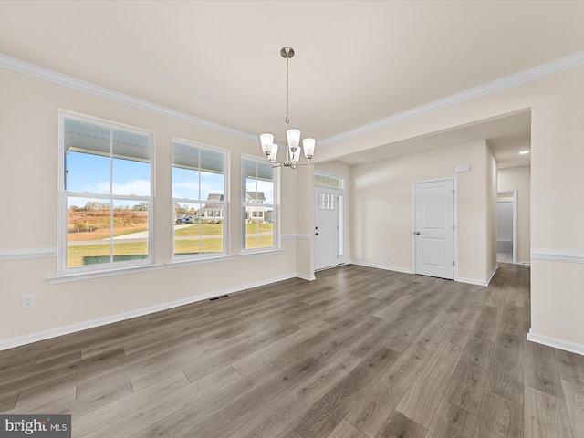 unfurnished dining area featuring crown molding, hardwood / wood-style floors, and a chandelier