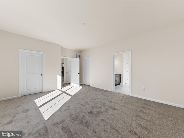 unfurnished bedroom with light colored carpet and ensuite bath