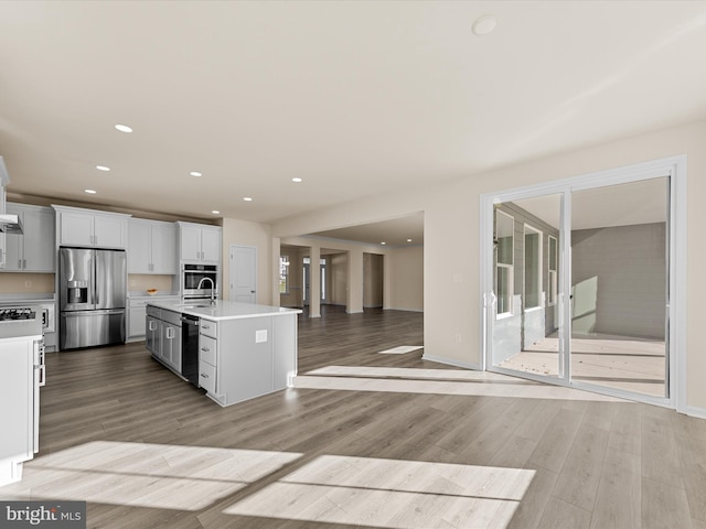 kitchen featuring a center island with sink, sink, light wood-type flooring, white cabinetry, and stainless steel appliances