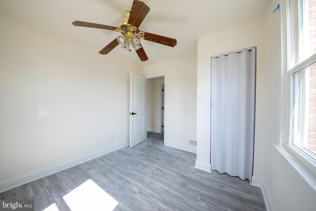 unfurnished bedroom with ceiling fan, a closet, and wood-type flooring