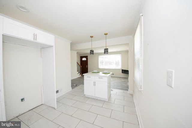 kitchen featuring light tile patterned floors, white cabinets, hanging light fixtures, and ornamental molding