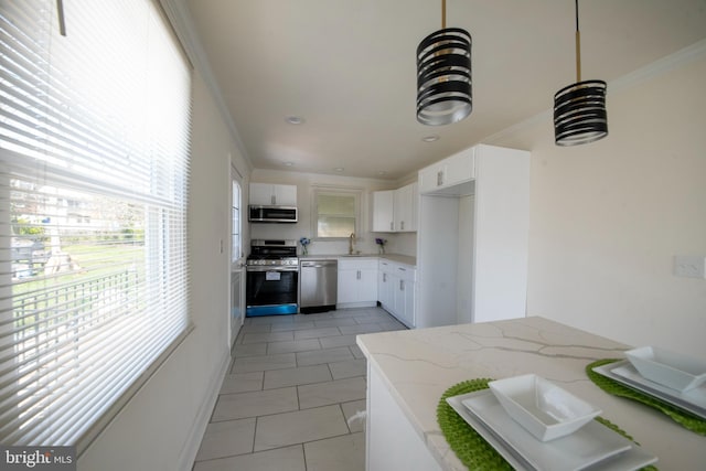 kitchen featuring appliances with stainless steel finishes, light stone counters, a wealth of natural light, and white cabinets