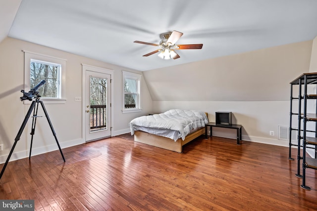 bedroom featuring ceiling fan, multiple windows, vaulted ceiling, wood-type flooring, and access to exterior