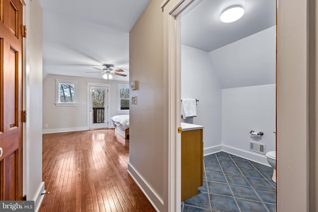 hallway featuring dark wood-type flooring and vaulted ceiling