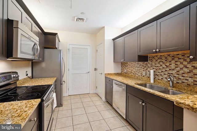 kitchen featuring light stone countertops, light tile flooring, sink, stainless steel appliances, and tasteful backsplash