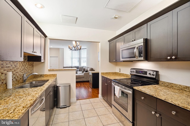 kitchen with light tile flooring, an inviting chandelier, stainless steel appliances, sink, and light stone countertops