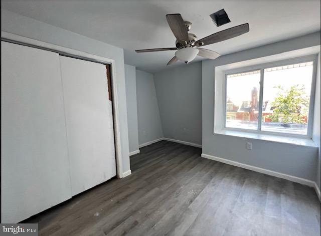 unfurnished bedroom with a closet, ceiling fan, and dark wood-type flooring