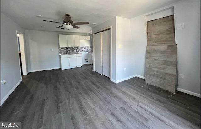 unfurnished bedroom featuring ceiling fan, a closet, and dark wood-type flooring