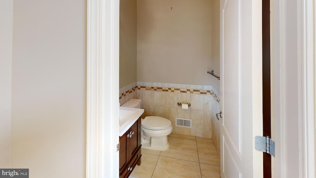 bathroom featuring toilet, tile walls, tile flooring, and vanity