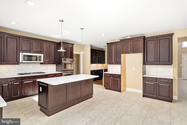 kitchen with appliances with stainless steel finishes, pendant lighting, a center island, and light tile floors