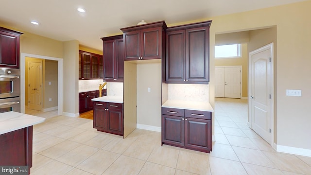 kitchen with backsplash, double oven, and light tile floors