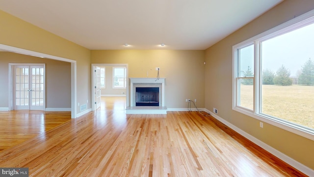 unfurnished living room featuring light wood-type flooring and french doors