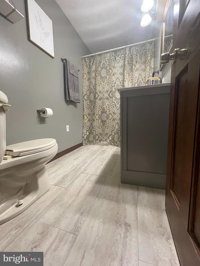 bathroom with tile flooring, toilet, vanity, and a textured ceiling