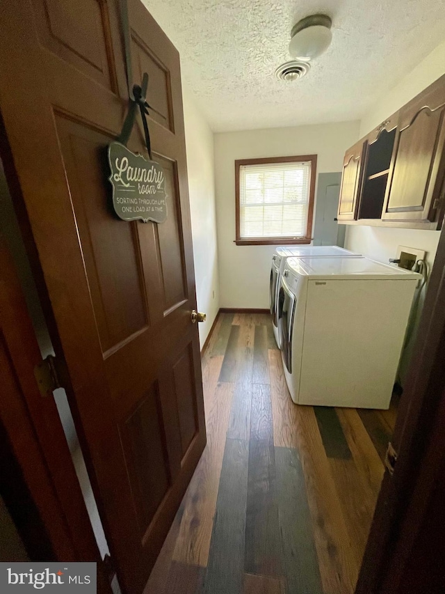 laundry room with washer hookup, a textured ceiling, cabinets, dark wood-type flooring, and washer and clothes dryer