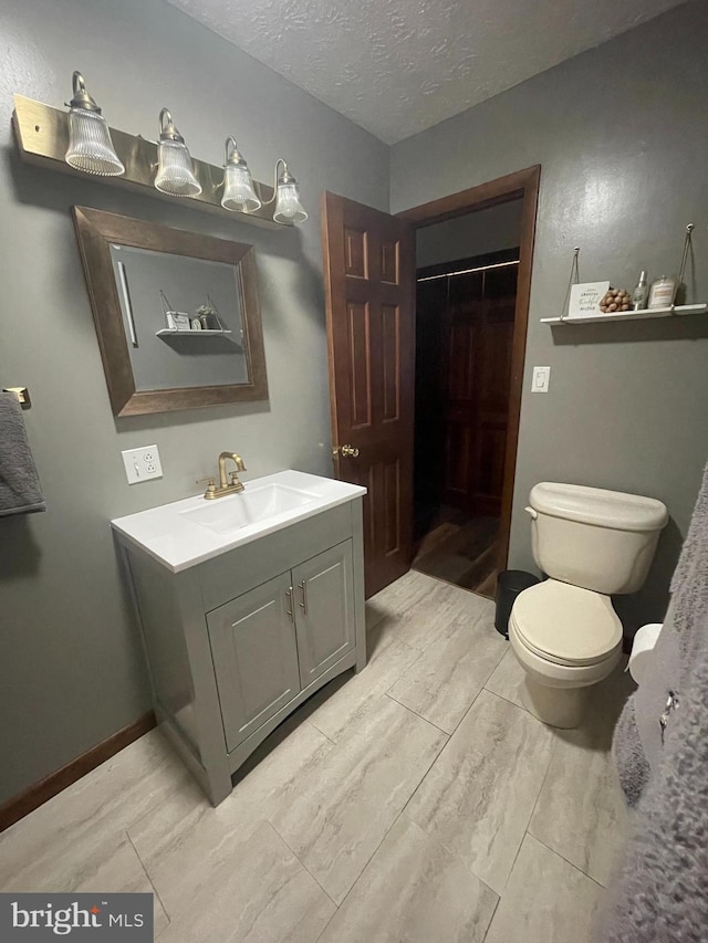 bathroom featuring toilet, vanity, and a textured ceiling