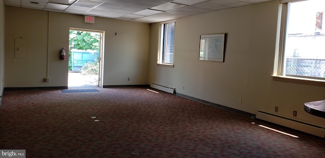 carpeted empty room featuring a paneled ceiling, a baseboard radiator, and a healthy amount of sunlight