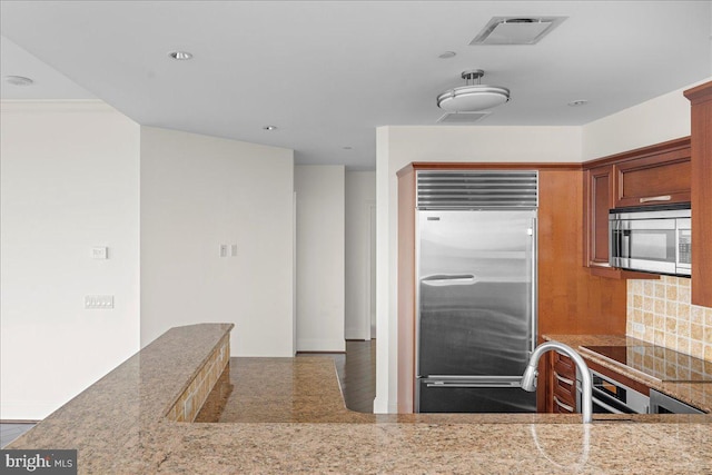 kitchen featuring backsplash, light stone counters, dark hardwood / wood-style flooring, and stainless steel appliances