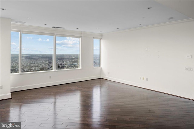 empty room featuring ornamental molding, dark wood-type flooring, and a wealth of natural light