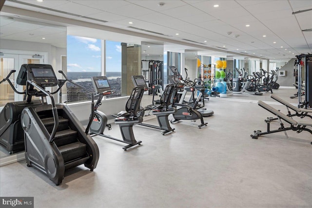 workout area featuring a paneled ceiling and a wall of windows