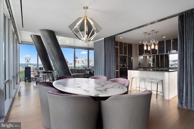 dining area featuring a notable chandelier, light hardwood / wood-style floors, and a wall of windows