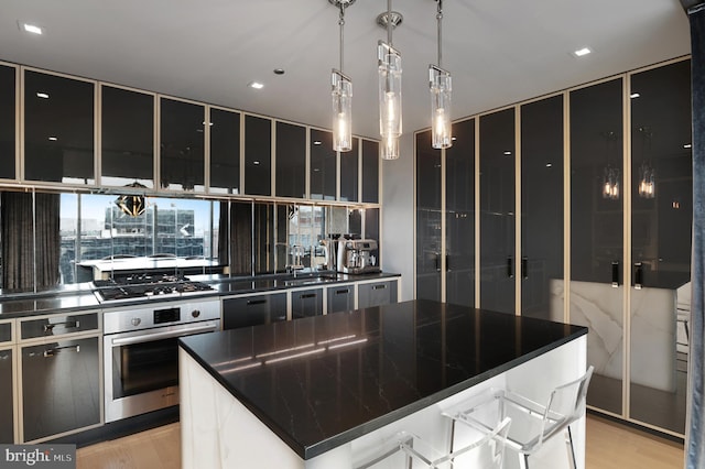 kitchen with pendant lighting, a kitchen island, a breakfast bar area, light hardwood / wood-style floors, and stainless steel appliances