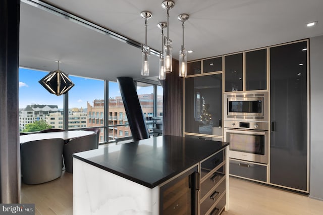 kitchen with appliances with stainless steel finishes, pendant lighting, light wood-type flooring, a center island, and wine cooler