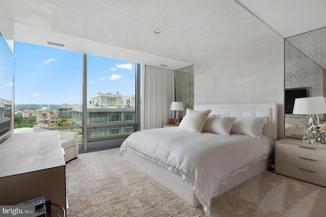 bedroom featuring light carpet, expansive windows, and multiple windows