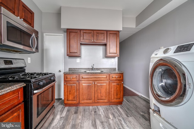 washroom with washer / clothes dryer, sink, and dark wood-type flooring