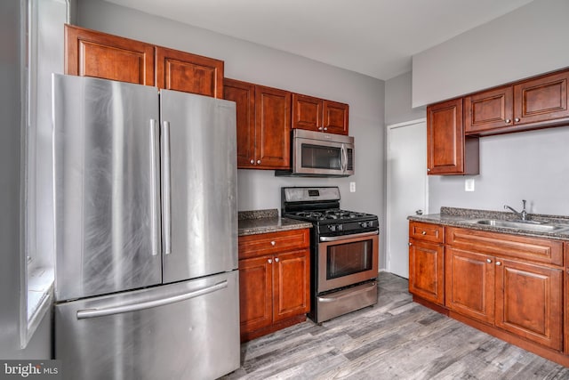 kitchen featuring dark stone counters, light hardwood / wood-style flooring, appliances with stainless steel finishes, and sink