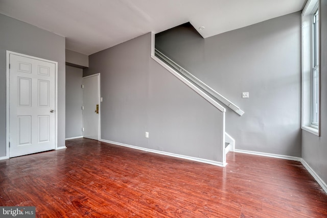 unfurnished living room featuring a healthy amount of sunlight and dark hardwood / wood-style flooring