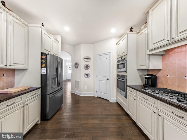 kitchen featuring dark hardwood / wood-style floors, backsplash, white cabinetry, and appliances with stainless steel finishes