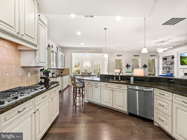 kitchen with appliances with stainless steel finishes, dark wood-type flooring, ceiling fan, decorative light fixtures, and white cabinets