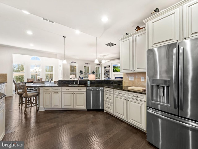 kitchen featuring dark hardwood / wood-style floors, appliances with stainless steel finishes, tasteful backsplash, and kitchen peninsula