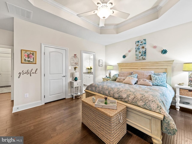 bedroom featuring ceiling fan, a raised ceiling, dark hardwood / wood-style flooring, crown molding, and ensuite bathroom