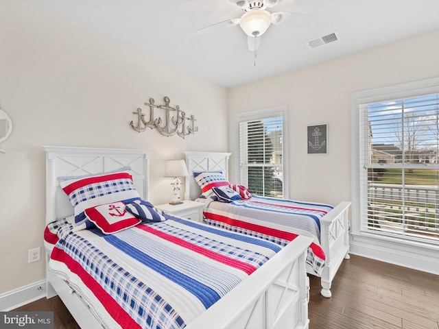 bedroom with ceiling fan, multiple windows, and dark wood-type flooring