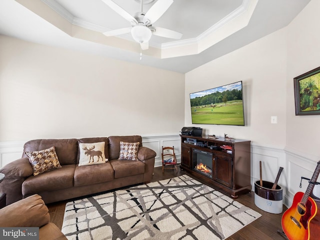 living room featuring ceiling fan, light hardwood / wood-style floors, ornamental molding, and a tray ceiling