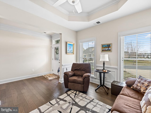 living room with ceiling fan, crown molding, dark wood-type flooring, and a raised ceiling