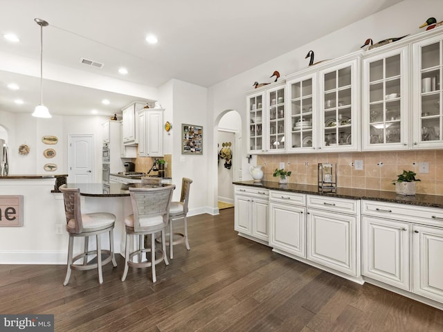 kitchen featuring white cabinets, a breakfast bar area, tasteful backsplash, and dark hardwood / wood-style floors