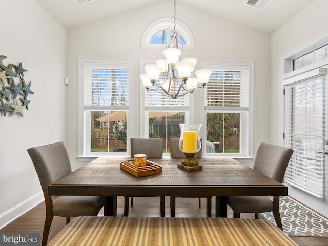 dining area with an inviting chandelier, dark wood-type flooring, and vaulted ceiling