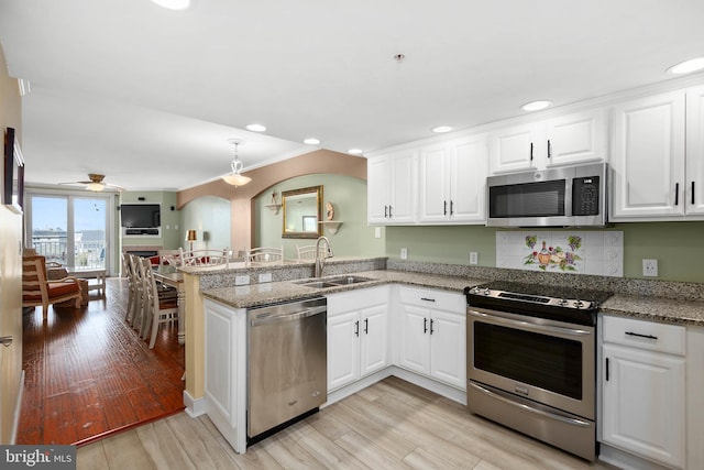 kitchen featuring ceiling fan, appliances with stainless steel finishes, sink, light wood-type flooring, and white cabinets