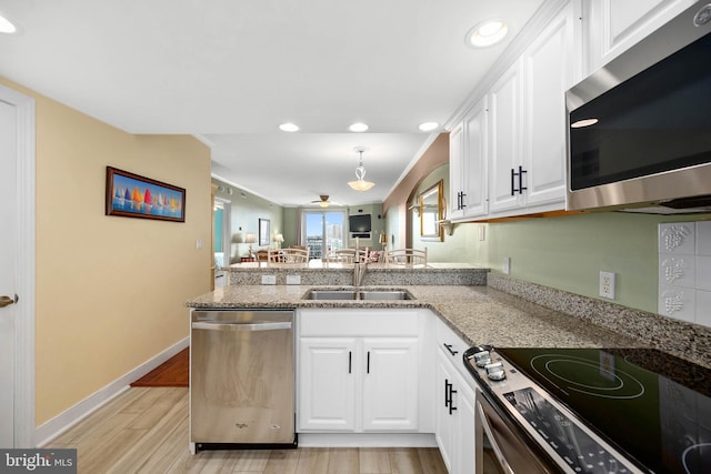 kitchen featuring white cabinetry, appliances with stainless steel finishes, light wood-type flooring, and light stone counters