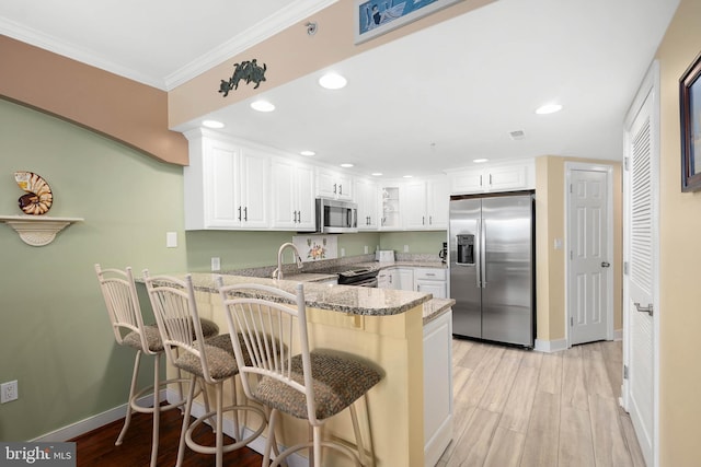 kitchen featuring white cabinets, stainless steel appliances, kitchen peninsula, light hardwood / wood-style flooring, and stone counters