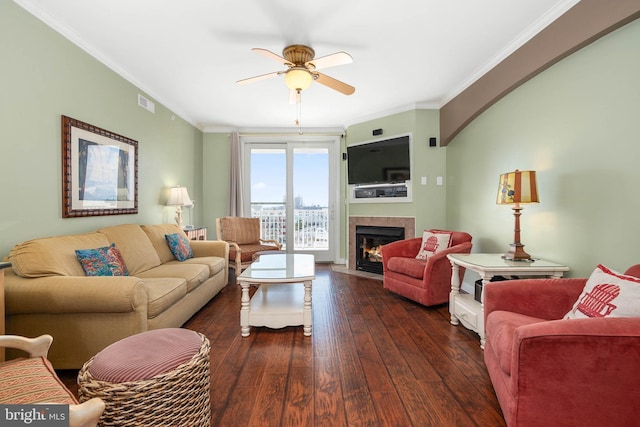 living room with a fireplace, dark wood-type flooring, ornamental molding, and ceiling fan