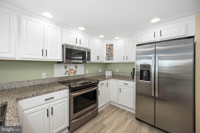 kitchen featuring white cabinets, stone counters, light hardwood / wood-style flooring, and stainless steel appliances