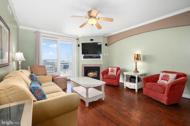 living room with ceiling fan, ornamental molding, dark wood-type flooring, and a fireplace