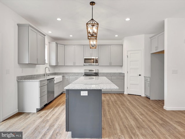 kitchen featuring pendant lighting, gray cabinetry, light wood-type flooring, stainless steel appliances, and a center island